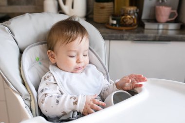 Yüksek sandalyedeki erkek bebeğin portresi. Önce küçük çocuk besleniyor. Otantik çocukluk anı. Yaşam tarzı kavramı.