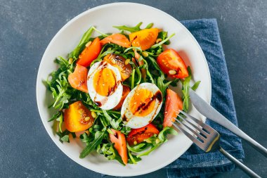 Taze domates, roka, somon, yumurta ve susamlı sağlıklı vejetaryen salatası. Diyet menüsü. Üst görünüm.