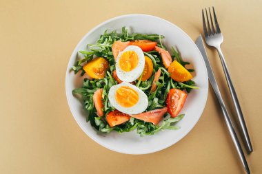 Taze domates, roka, somon, yumurta ve susamlı sağlıklı vejetaryen salatası. Keto diyet menüsü. Üst görünüm.