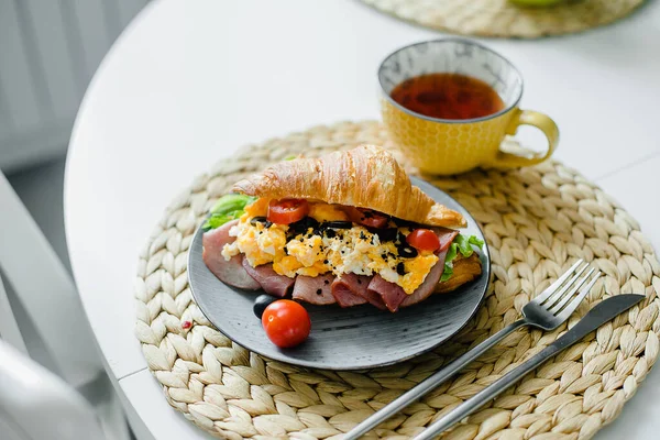 Здоровый Завтрак Тарелка Бутербродом Круассаном Ветчиной Яичницей Помидорами Чаем Столе — стоковое фото