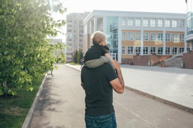 Baba parkta oğlunu omuzlarında taşıyordu. Babasıyla dışarıda oynayan sevimli çocuk. Yaz yaşam tarzı konsepti