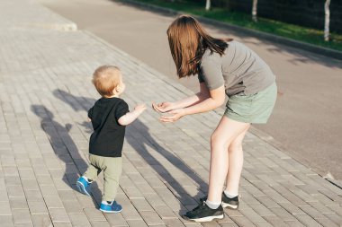 Küçük kardeşi olan bir kız birlikte yürüyor. Bebek, ablasının yardımıyla ilk adımı atıyor. Otantik an, yaz yaşam tarzı konsepti