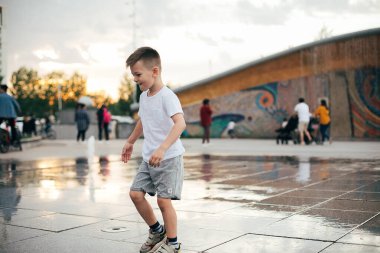 Oğlan sıcak yaz gününde sokak çeşmesinde iyi eğlenceler. Yaşam tarzı, özgün, açık hava aktiviteleri konsepti.