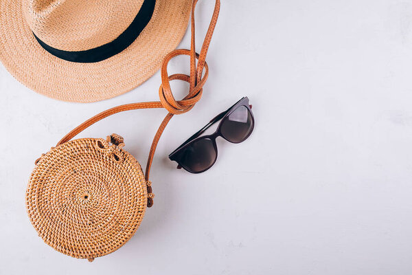 Summer beach accessories. Female summer travel fashion concept. Straw bag, round rattan bag, sunglasses on white background. Top view, flat lay, copy space