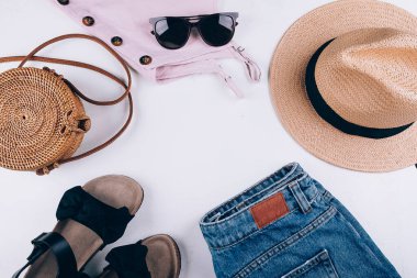 Yaz boyunca hayat devam eder. Sıradan kadın kıyafetleri, aksesuarlar. Üstü, şort, organik rattan çanta, hasır şapka, sandalet, güneş gözlüğü. Tatil, seyahat konsepti. Üst görünüm düzlüğü