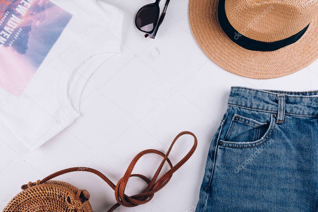 Overhead summer still life. Casual women's clothing, acccessories. T-shirt, shorts, organic rattan bag, straw hat, sunglasses. Vacation, travel concept. Top view flat lay