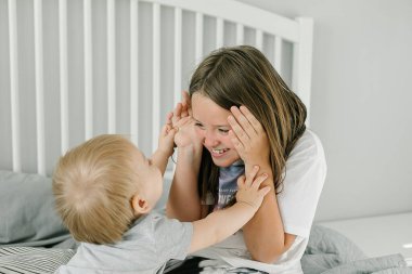 Beyaz yatak odasında oynayan mutlu çocuklar. Erkek ve kız kardeş yatakta saklambaç oynuyor. Aile Hayatı Konsepti