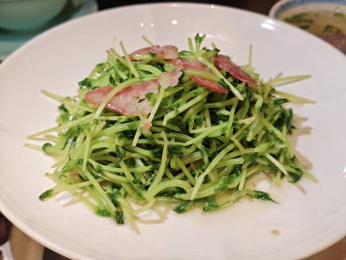 Taze yeşil fasulye filizi. Beyaz tabakta domuz pastırması ve yenir.