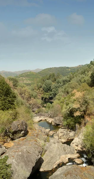 Dağ nehri manzarası, kayaların ortasında küçük bir gölet ve güneşlenen insanlar, yaz ve sıcak, tatiller ve eğlence.