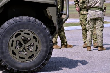 Bir askeri aracın önünde ve önünde duran bir grup asker de ayakta duruyor, ordu.