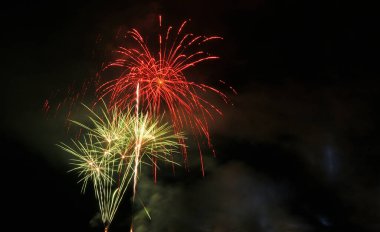 Havai fişek patlamalarıyla dolu gece gökyüzü, yeşil ve kırmızı, önemli bir günü kutluyor ve kutluyor.