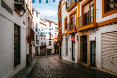 İspanya, Cordoba 'dan Rodriguez Marin' i arayın. Geleneksel beyaz evler, canlı sarı aksanlar ve açık gökyüzü altında bayram sancakları.