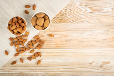 Kırsal arka planda, ahşap kasede bir yığın badem ve fotokopi alanı. Kabuklu bademler ve soyulmuş fındıklar üst görünüm