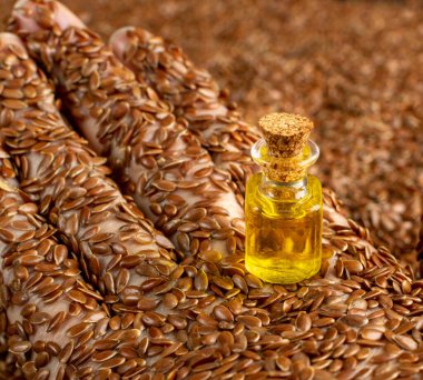 Keten tohumu yağı küçük bir şarap şişesinde. Elde keten tohumu dokusu, organik temel yağ sanatı konsepti