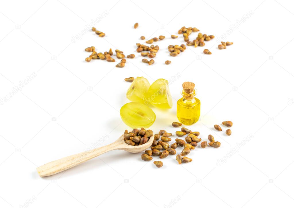 Grape oil seed in small vintage bottle isolated on white background. Heap of grape seeds with green slices and cold press organic essential oil, tincture, extract, infusion