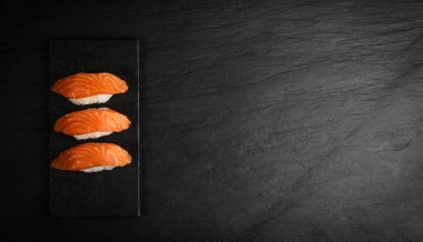 Nigiri Suşi ve Ham Somon fileto Black Stone Arka plan Üst Manzarası. Taze Kırmızı Balık Kalın Parçaları ya da Kopya Alanı olan Alabalık Suşisi