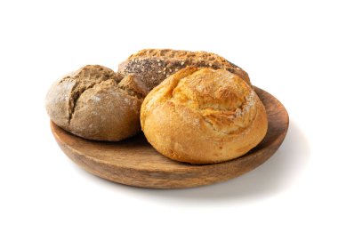 Üç çeşit tohum karışımlı yuvarlak çörek. Tahta tabakta küçük yuvarlak kahverengi ekmek ruloları ve beyaz glütensiz ekmek rulosu.