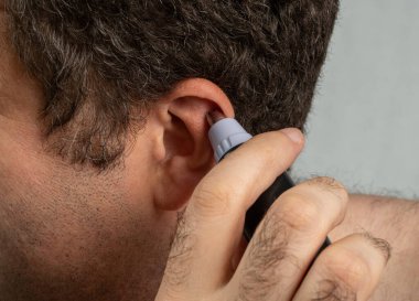 Bir adam kulağındaki kılları yakın plan çekimle alıyor. Tıraş makinesi, elektrikli saç kesme makinesi reklamı