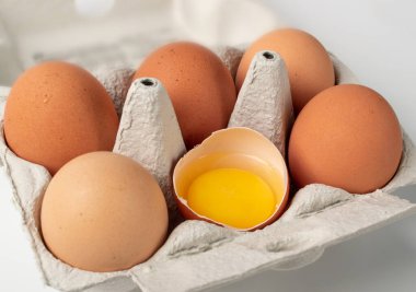 Altı yumurta ve kırık bir yumurtanın olduğu kutuyu aç. Kutu veya yumurta kabında taze organik tavuk yumurtası.