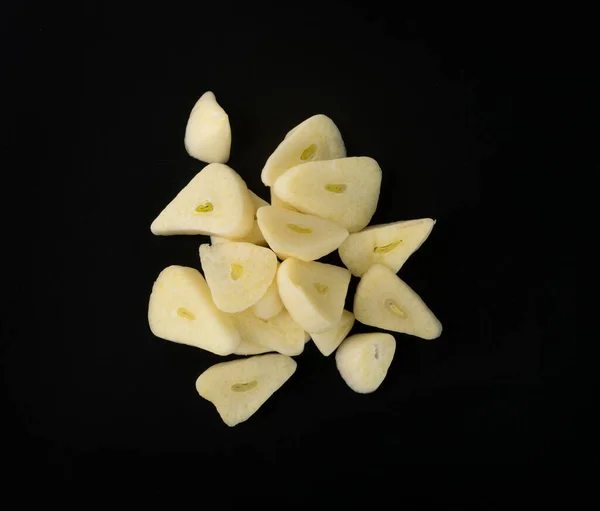 Fresh sliced garlic isolated on black background closeup. Macro shot of chopped crushed garlic cloves, cut into pieces food ingredient