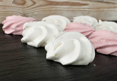 Beyaz ve pembe kurabiyeler yakın plan. Geleneksel çırpma kremi, fırında çırpma kremi ya da bulanık arka planda beze.
