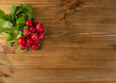 Üst görüş radarı ahşap kırsal arka planda fotokopi alanı olan bir grup. Taze turp kökü maketi, yeşil yapraklı kırmızı turp yığını