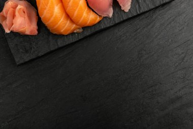 Somon nigiri suşi ve maguro ton balığı suşi maketi. Susi, ham kırmızı balıkla rulo şeklinde koyu taştan tabakta fotokopi alanı ile hazırlandı.