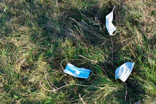 Mask pollution concept. Disposable medical masks on park grass background. Disposable medic mask waste, ppe environment damage