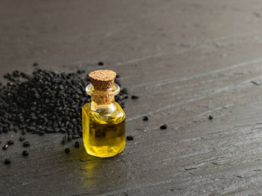 Ahşap masanın üzerinde küçük bir şişe içinde siyah kimyon yağı. Karanfil tohumları organik yağ, tentür, özü, zerk. Nigella sativa tentürü, özü