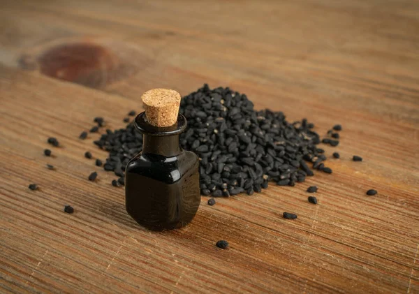 Black cumin oil in small vintage bottle on wood table. Caraway seeds organic essential oil, tincture, extract, infusion. Nigella sativa tincture, essence