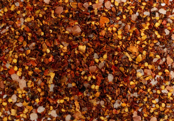 Red chilli pepper flakes texture background. Broken crushed hot red pepper pattern, dried chili flake wallpaper top view with copy space
