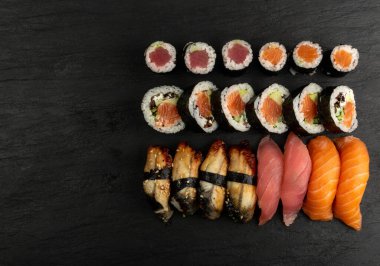 Dark Sate Tabağı Üst Manzaralı Çeşitli Japon Suşi Yemekleri. Nigiri ve Nori Maki Suşi Rolls with Raw Somon, Maguro Tuna, Unagi Yılanbalığı, Avocado, Salatalık, Yeşil Salata ve Philadelphia Peyniri