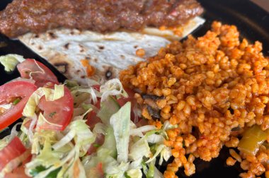 Bulgur, salata ve lavaşlı Türk usulü tavuk kebabı. Arka planda baharatlı ızgara et.