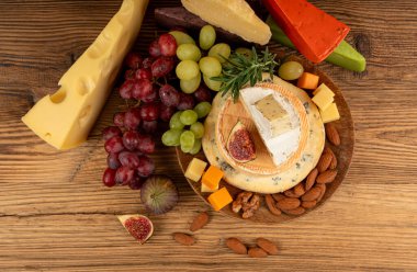 Peynir tabağı çeşitliliği, sarı, beyaz ve mavi gorgonzola tabağı, Munster, dört peynirli pano, çeşitli doğranmış süt ürünleri, ahşap üzerinde kokulu Fransız peyniri.