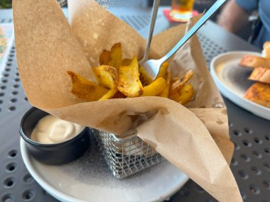 Kağıt kabuklu kızarmış cips çubukları. Lokantada patates cipsi, patates kızartması, patates kızartması, patates kızartması, beyaz soslu kızarmış patates, arka planda bulanık patates kızartması.