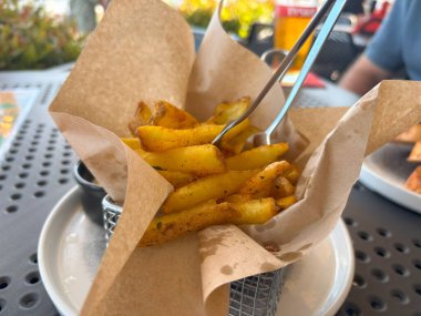 Kağıt kabuklu kızarmış cips çubukları. Lokantada patates cipsi, patates kızartması, patates kızartması, patates kızartması, beyaz soslu kızarmış patates, arka planda bulanık patates kızartması.