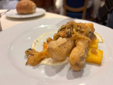 Restoran tabağında lezzetli balık var. Kızarmış morina filetosu ile İngiliz yemeği. Polenta çubukları yakın plan, bulanık arkaplan.