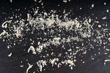 Siyah arka planda rendelenmiş mozzarella peyniri. Parçalanmış mozarella dokusu, süt ürünleriyle yemek pişirme pizza veya makarna için beyaz İtalyan mozzarella şeritleri yakın çekim ve üst manzara.