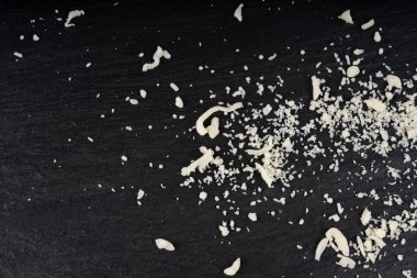 Siyah arka planda rendelenmiş mozzarella peyniri. Parçalanmış mozarella dokusu, süt ürünleriyle yemek pişirme pizza veya makarna için beyaz İtalyan mozzarella şeritleri yakın çekim ve üst manzara.