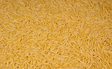Çiğ orzo makarna yığını dokulu arka plan. Pirinç tanesi şeklinde risoni makarnası, Yunan Kritharaki desenli üst görünüm