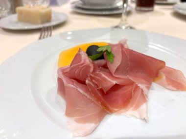 Prosciutto dilimleri beyaz tabakta. İspanyol jamonu, restoranda kavun, makro fotograf parma jambonu, Serrano ya da Iberico yakın plan bulanık.