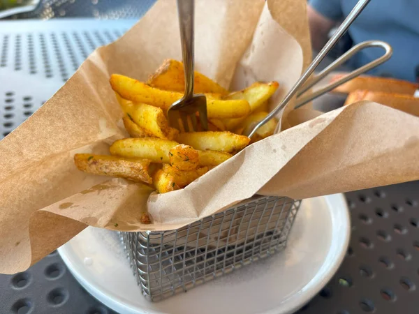 Kağıt kabuklu kızarmış cips çubukları. Lokantada patates cipsi, patates kızartması, patates kızartması, patates kızartması, beyaz soslu kızarmış patates, arka planda bulanık patates kızartması.