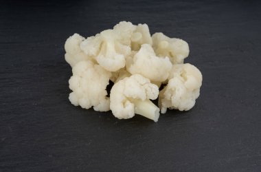 Buharda pişmiş karnabahar parçaları. Kaynamış karnabahar çiçekleri, siyah arka planda pişmiş cauli çiçekleri.