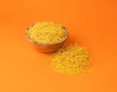 Turuncu arka planda çiğ vermicelli, yuvarlak altın çorba makarna, küçük ev yapımı erişte, ince makarna, İtalyan sarısı filini makarna.