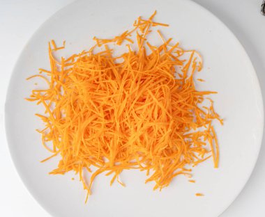 Taze rendelenmiş havuçlar, çiğ havuç parçaları yakın plan, doğranmış portakal kökü sebzesi, havuç küçük çubuklar beyaz arka plan üst görünümü