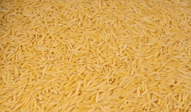 Çiğ orzo makarna yığını dokulu arka plan. Pirinç tanesi şeklinde risoni makarnası, Yunan Kritharaki desenli üst görünüm