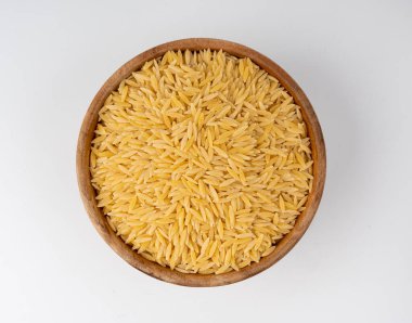 Kavanozda çiğ orzo makarna yığını. Pirinç tanesi şeklinde risoni makarnası. Beyaz arka plan manzaralı Yunan Kritharaki yığını.