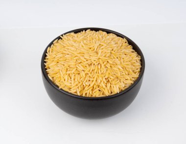 Kavanozda çiğ orzo makarna yığını. Büyük pirinç tanesine benzeyen risoni makarnası, beyaz arka planda Yunan Kritharaki yığını.