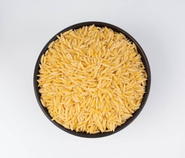 Kavanozda çiğ orzo makarna yığını. Pirinç tanesi şeklinde risoni makarnası. Beyaz arka plan manzaralı Yunan Kritharaki yığını.