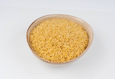 Kavanozda çiğ orzo makarna yığını. Büyük pirinç tanesine benzeyen risoni makarnası, beyaz arka planda Yunan Kritharaki yığını.